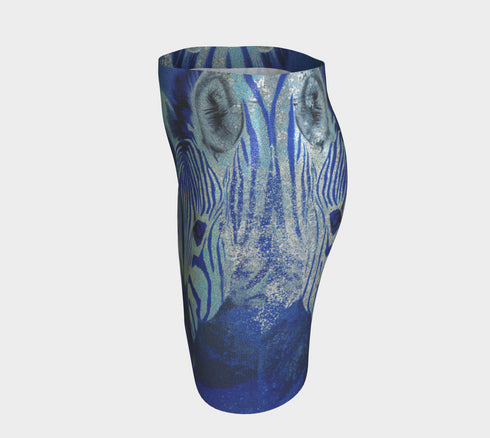 A high-waisted, bodycon mini skirt with a tight, fitted silhouette ending mid-thigh. The skirt features a vibrant, all-over graphic print of a mirrored zebra head in electric and royal blue tones against a dark blue, pixelated background. The zebra's stripes have a textured, glittery appearance in shades of silver and light blue. The skirt is made from a smooth, stretchy performance knit fabric with a subtle sheen, designed to hug the body's curves.